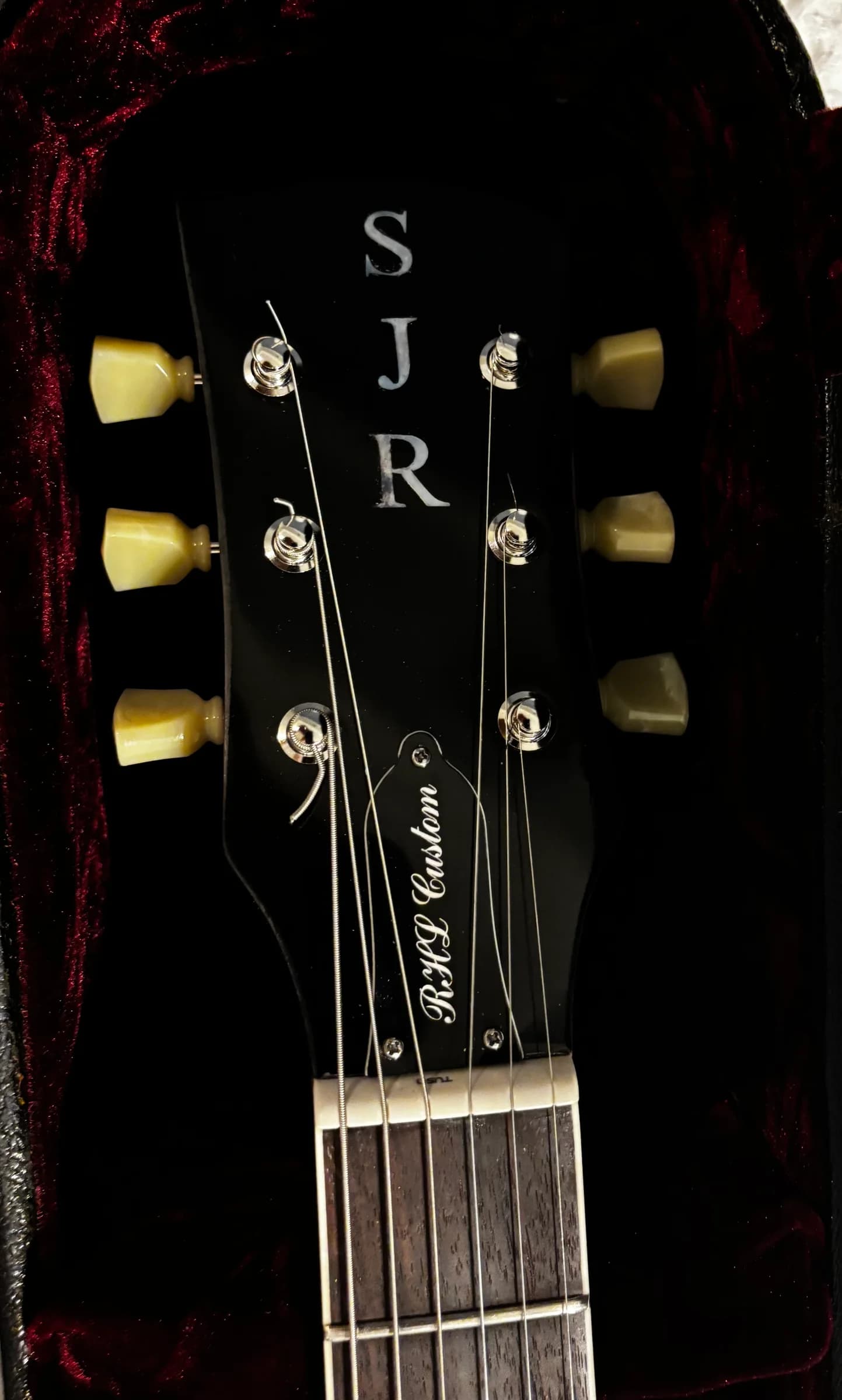 Black SJR headstock with cream tuner buttons in a red-lined case